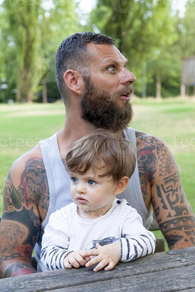 getatoeëerd vader hebben pret met zijn zoon in de park foto