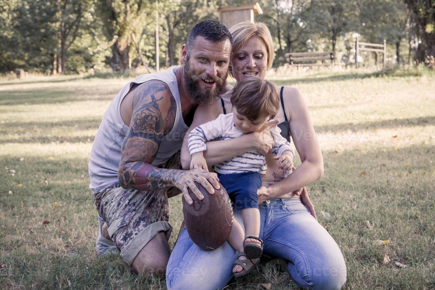 jong paar met kind hebben pret Bij de park met rugby bal foto