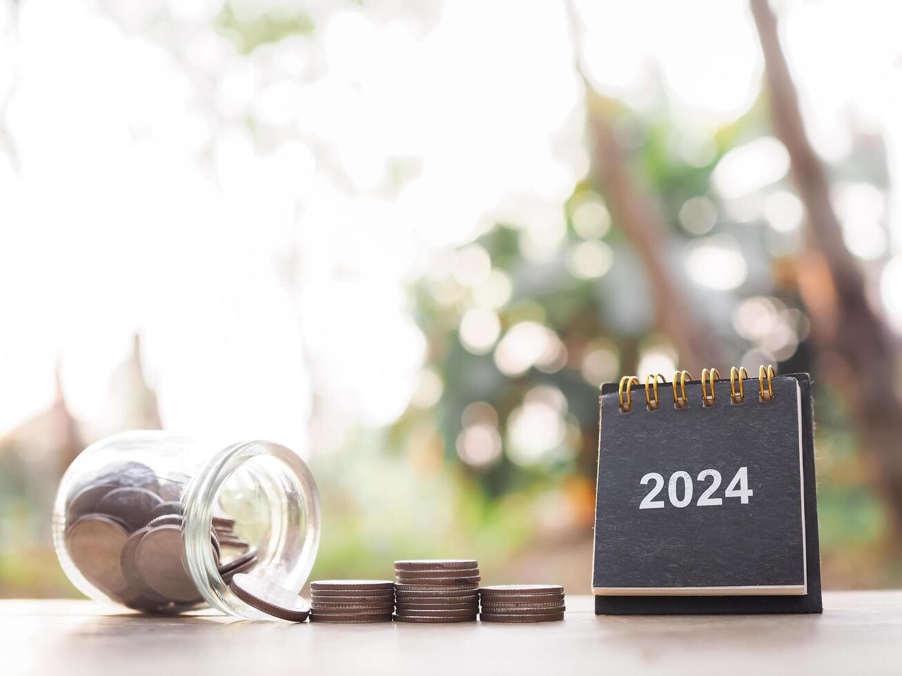 2024 bureau kalender en stack van munten. de concept van besparing geld, financieel, investering en bedrijf groeit in jaar 2024. foto