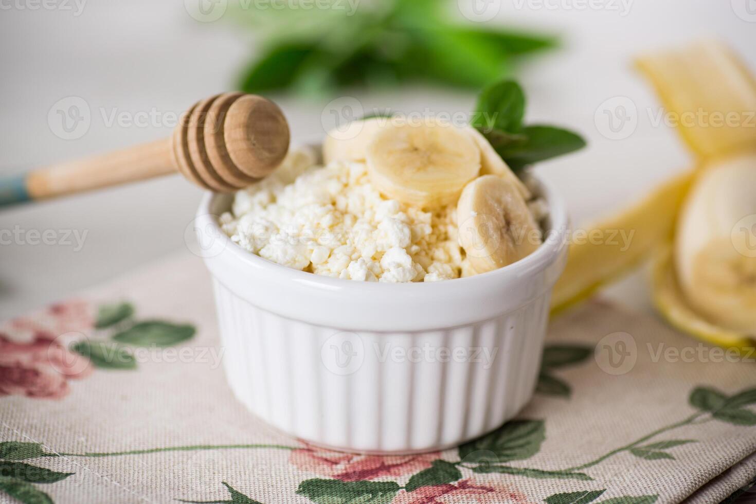 kruimelig biologisch huisje kaas met honing en bananen in een keramisch kom foto