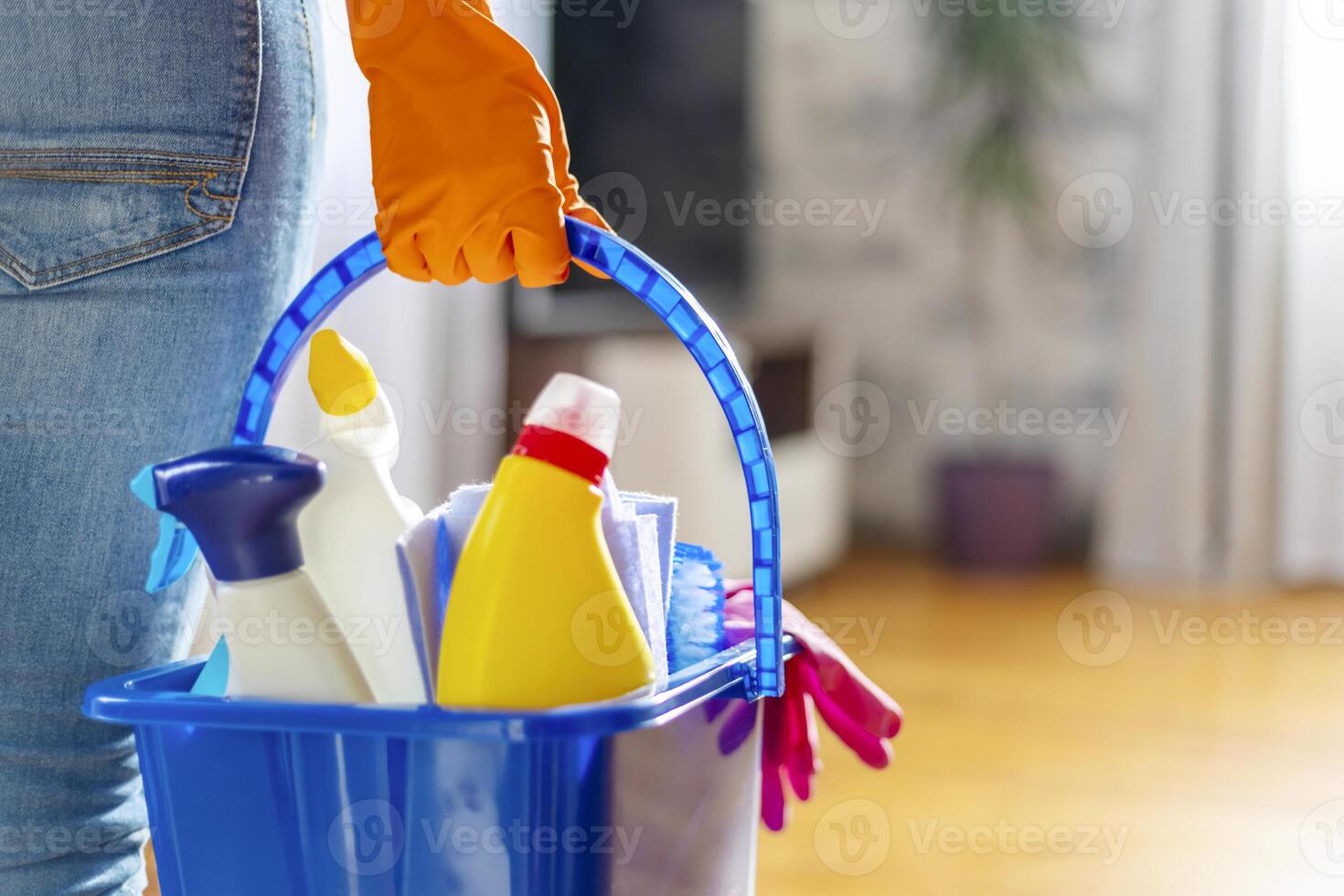 vrouw in rubber handschoenen met emmer van schoonmaak benodigdheden klaar naar schoon omhoog foto