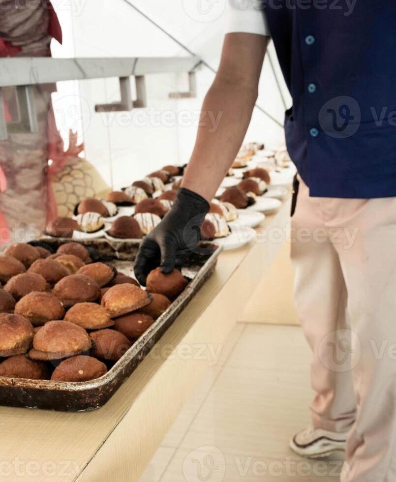 hotel medewerkers zijn voorbereidingen treffen tussendoortje cakes Aan borden voordat de ontmoeting. veel rijen van borden met buffet snacks. foto