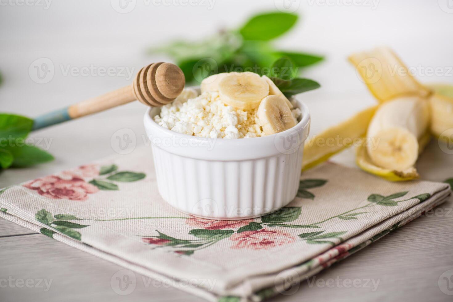 kruimelig biologisch huisje kaas met honing en bananen in een keramisch kom foto