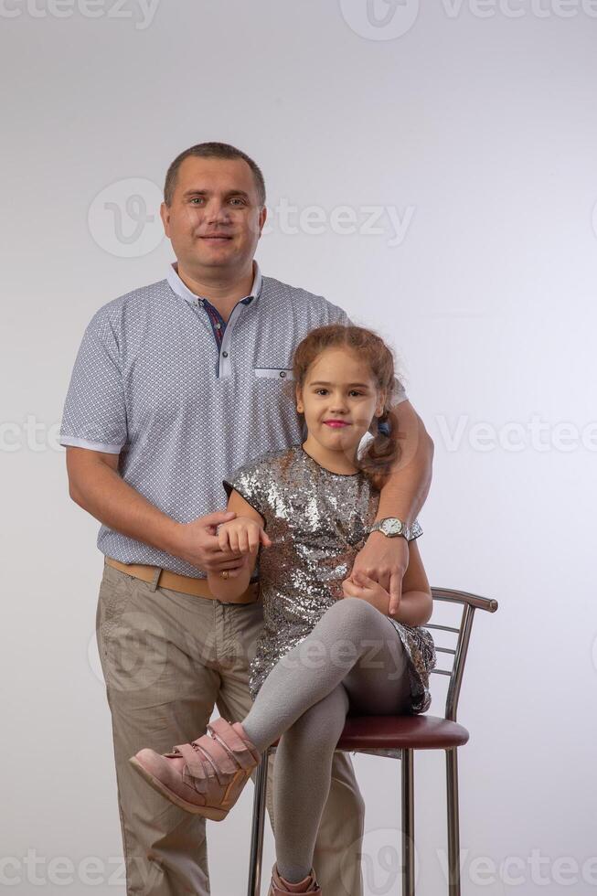 portret van lief dochter glimlachen en zittend Aan de nek van haar knap vader geïsoleerd over- grijs achtergrond 2 foto