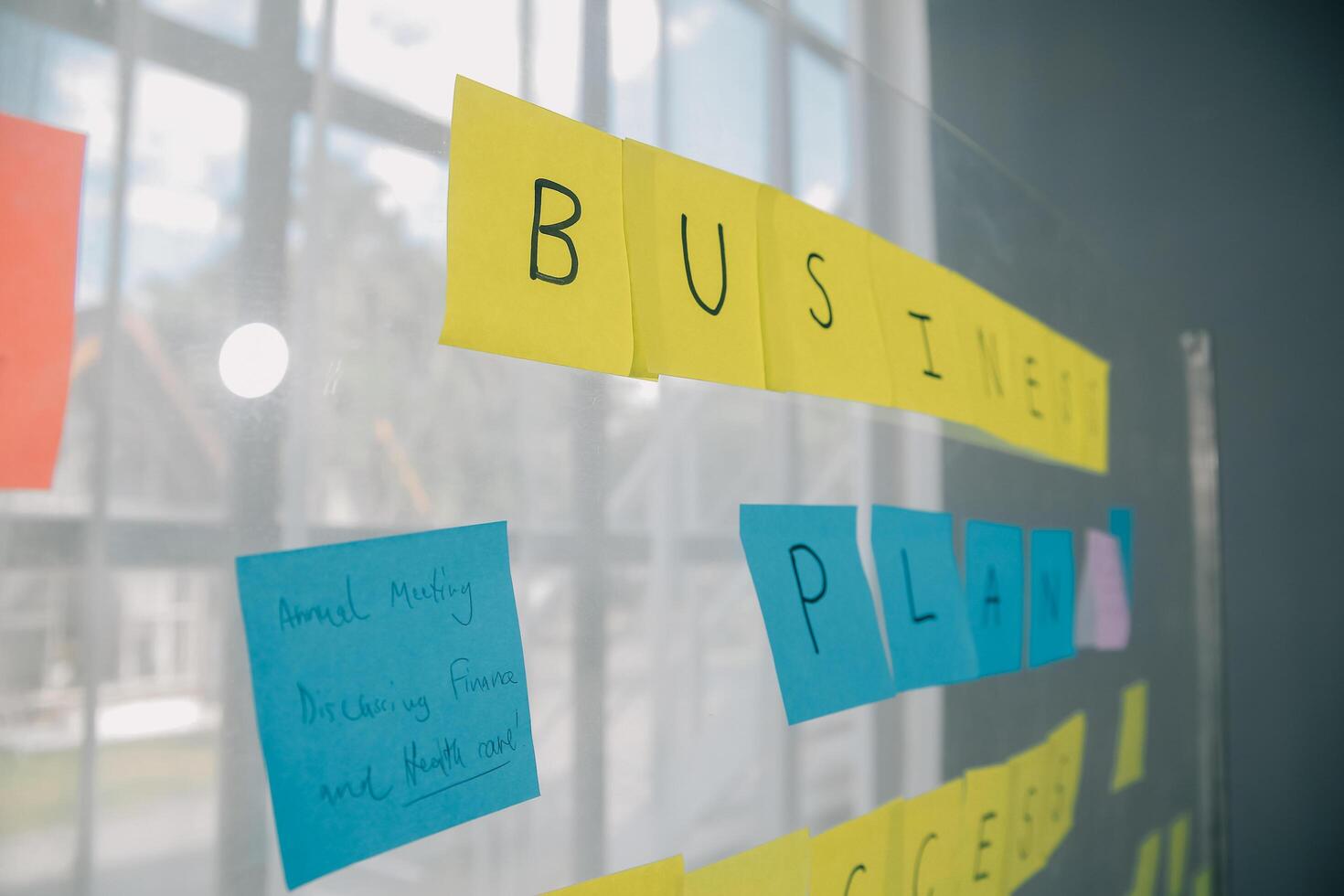 jong creatief team professioneel gebruik makend van post het aantekeningen in glas muur naar schrijven strategie bedrijf plan naar ontwikkeling toenemen naar succes. foto