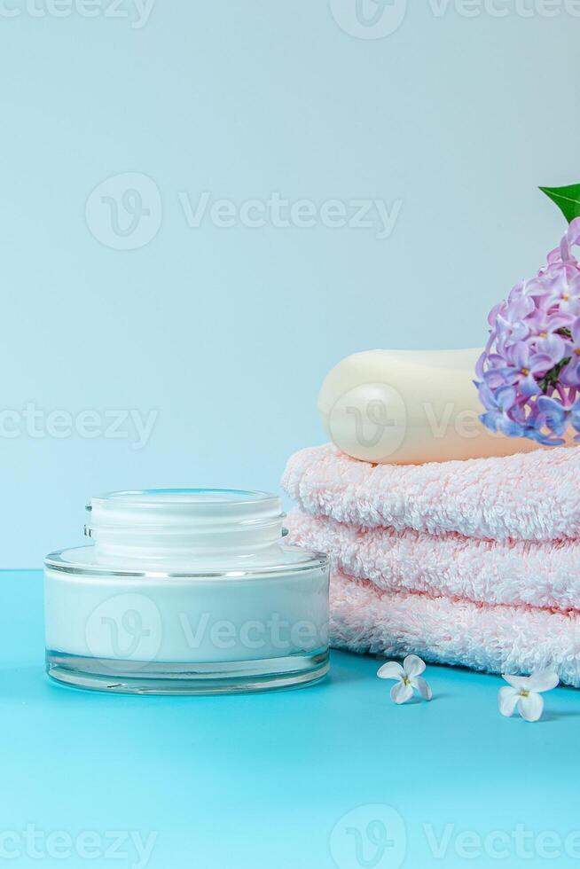 handdoek, room en zeep Aan achtergrond van delicaat lila bloemen. foto