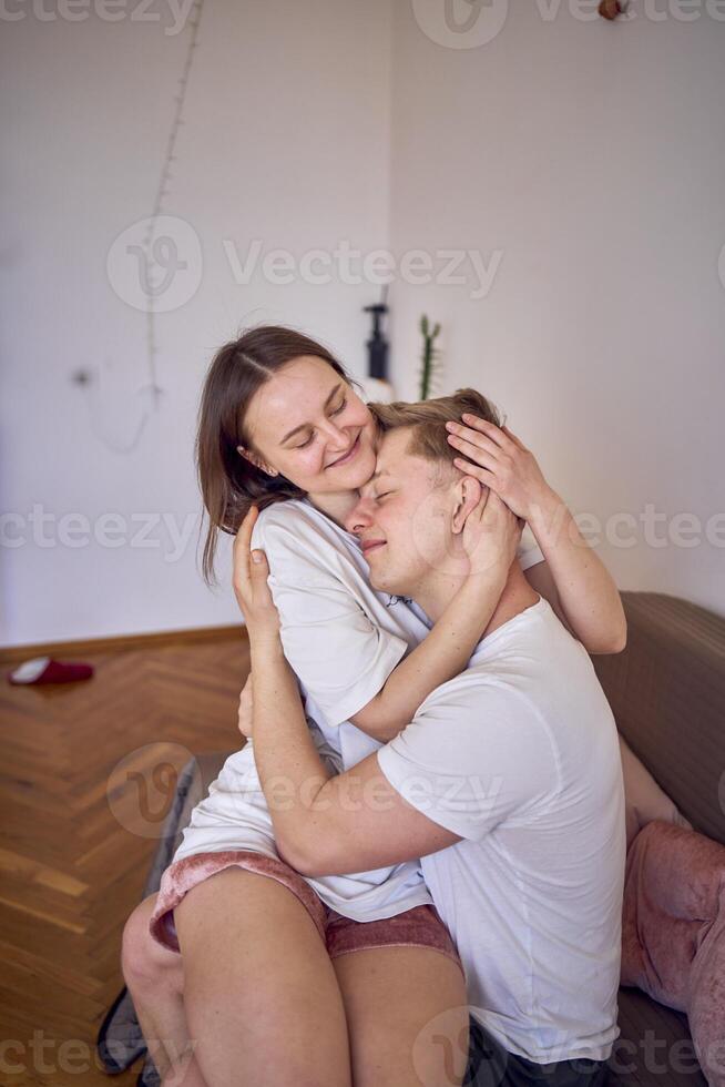 een jong paar in huis kleren voorzichtig knuffel in de leven kamer, minimalisme foto