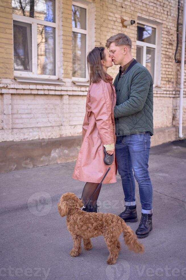 een jong paar in liefde wandelen door de voorjaar stad met een cockapoo foto