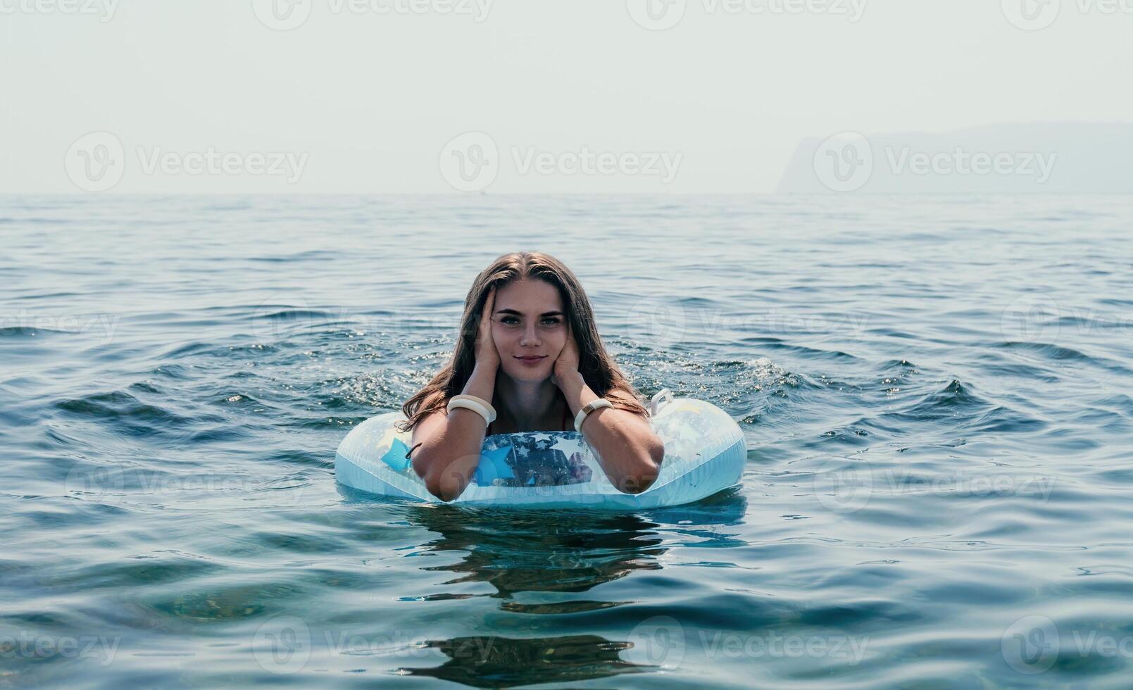 vrouw zomer zee. gelukkig vrouw zwemmen met opblaasbaar donut Aan de strand in zomer zonnig dag, omringd door vulkanisch bergen. zomer vakantie concept. foto