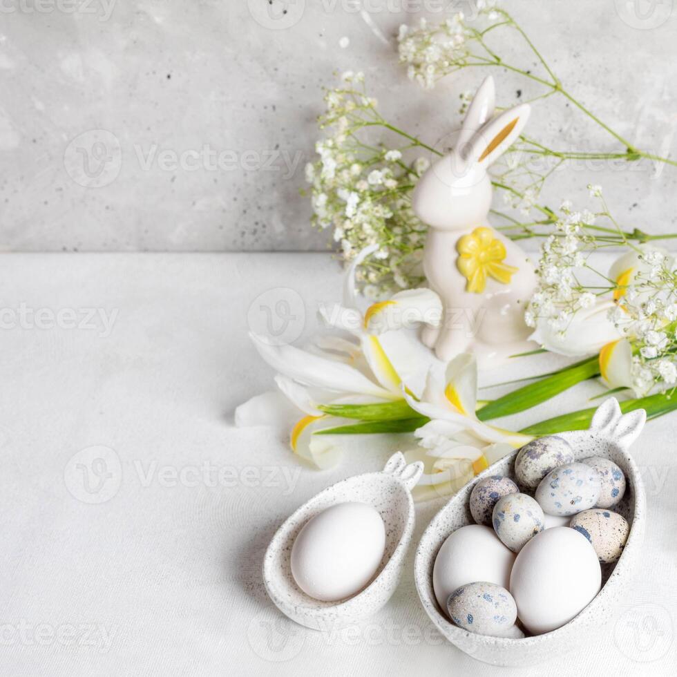 Pasen. natuurlijk eieren in dacht kommen met konijn oren, keramisch konijn, wit iris, gypsophila bloemen foto