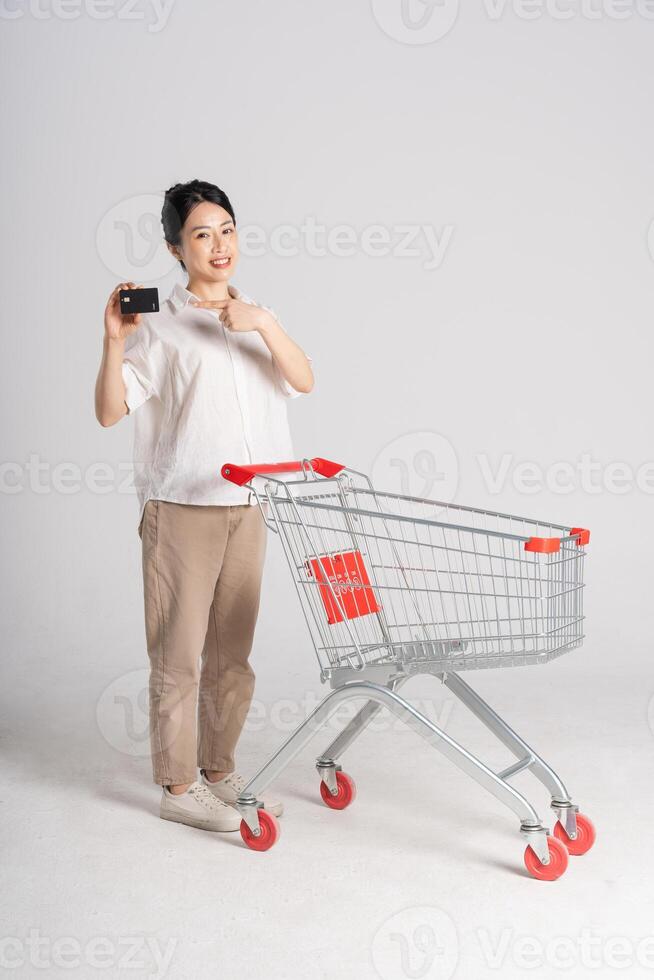 glimlachen vrouw gelukkig voortvarend een supermarkt kar, geïsoleerd Aan wit achtergrond foto