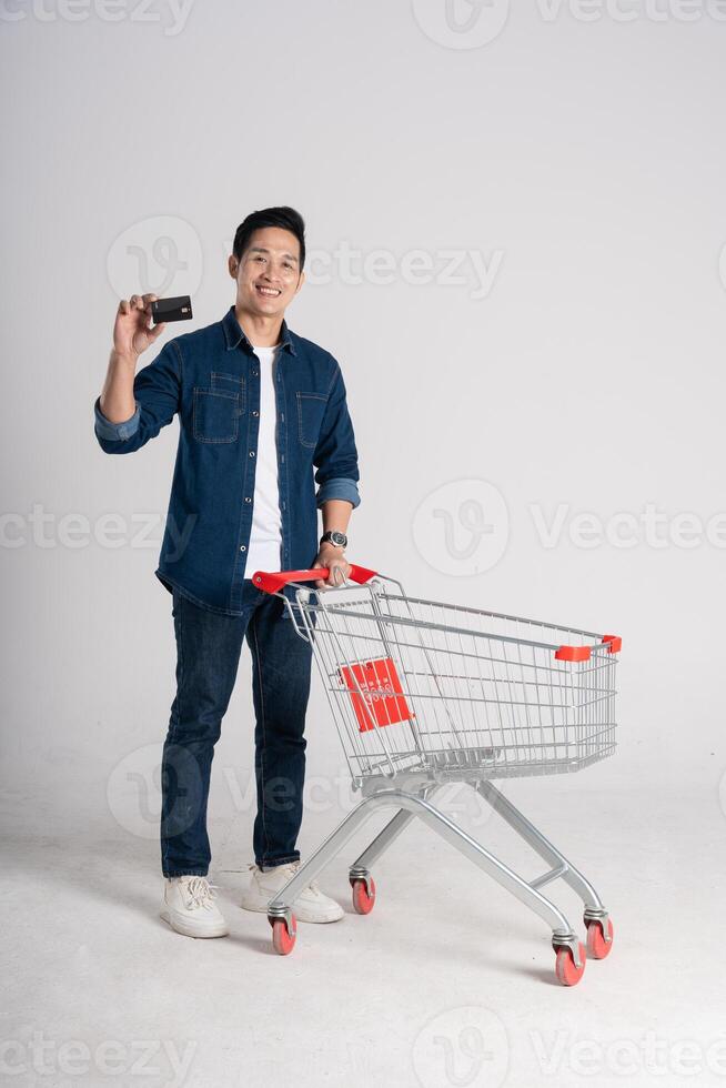 gelukkig glimlachen Mens voortvarend supermarkt kar geïsoleerd Aan wit achtergrond foto