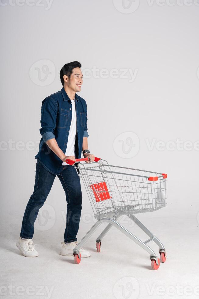 gelukkig glimlachen Mens voortvarend supermarkt kar geïsoleerd Aan wit achtergrond foto