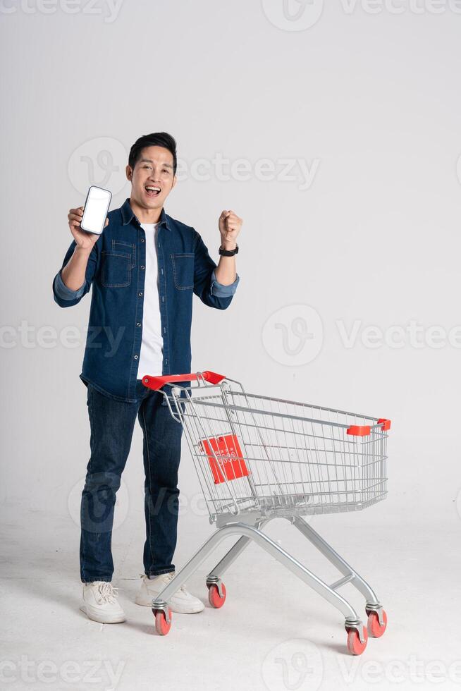 gelukkig glimlachen Mens voortvarend supermarkt kar geïsoleerd Aan wit achtergrond foto