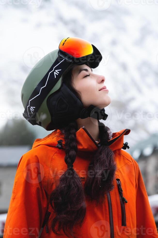 jong vrouw van Kaukasisch etniciteit looks naar de kant en glimlacht, verhogen haar hoofd naar de lucht, genieten van haar vakantie Bij de ski toevlucht foto