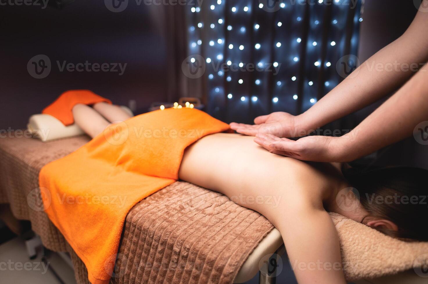 Mens geeft een terug massage naar een jong vrouw. massage therapeut massages terug met twee handen in massage kamer van massage spa centrum door kaarslicht foto