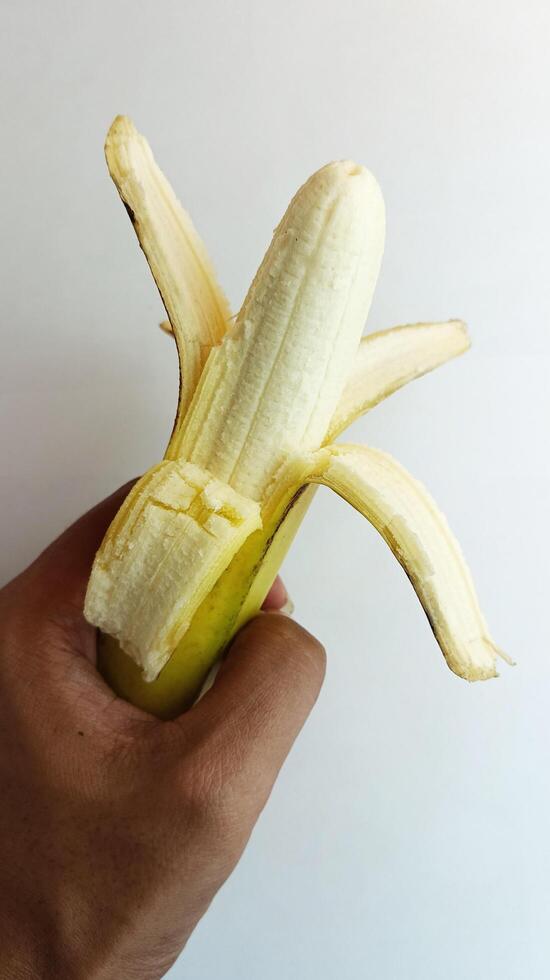 hand- Holding een geel banaan Aan een wit achtergrond foto