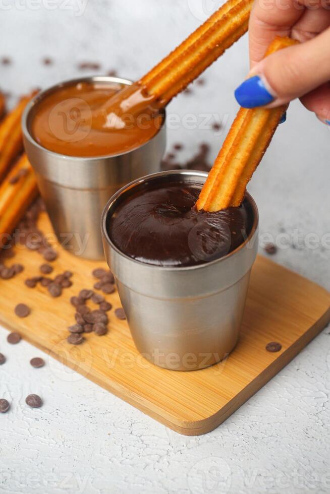 persoon dompelen aardbei in een kop van gesmolten chocola foto