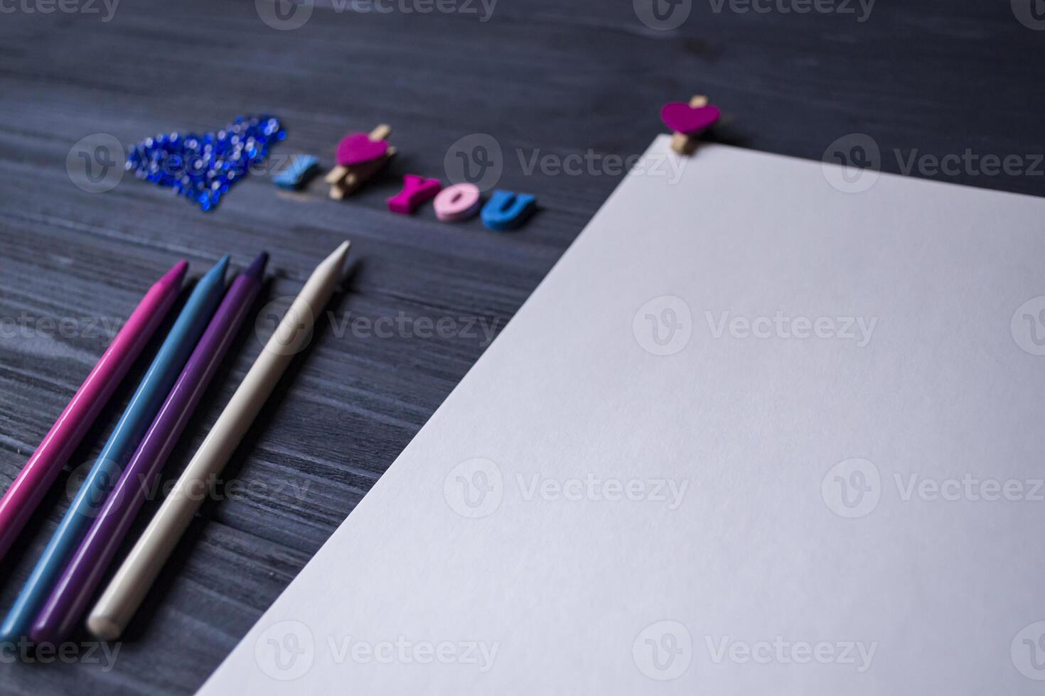 wit papier, kleurrijk potloden en decor Aan een blauw houten achtergrond. groet kaart foto
