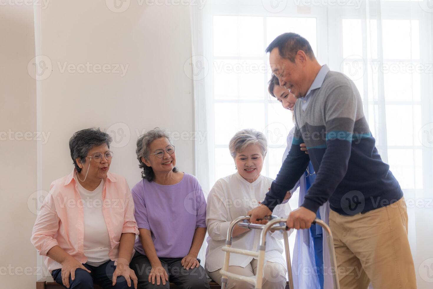 Aziatisch jong verpleegster ondersteuning senior ouder Mens wandelen met wandelaar. mooi verpleegster helpen en nemen zorg. ouderen volwassen opa geduldig aan het doen fysiek behandeling met een groep van senior vrienden in ziekenhuis. foto