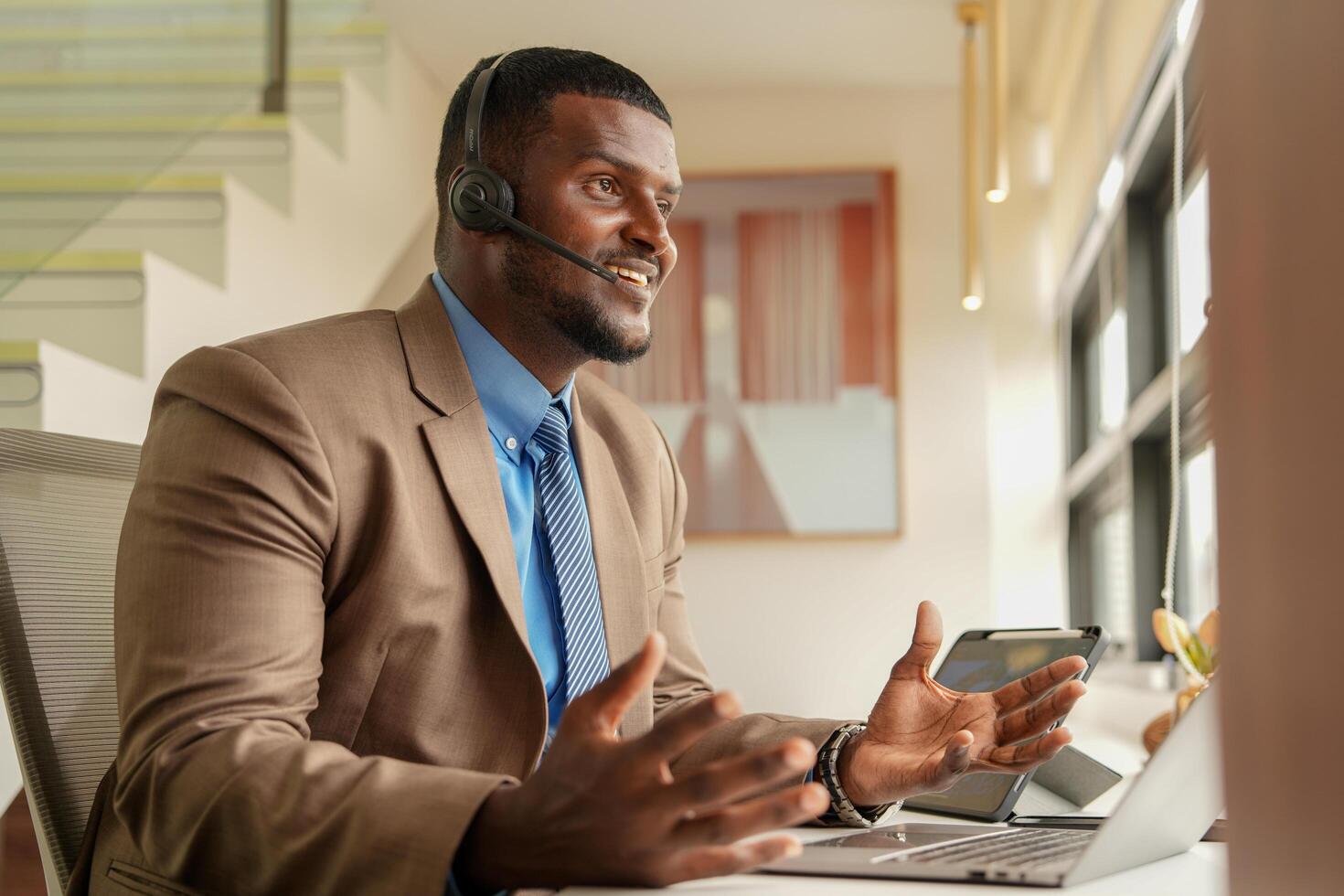 klant ondersteuning telefoontje centrum operator of receptioniste. klant onderhoud en Mens consultant pratend terwijl aan het doen een overleg online. Afrikaanse operator mannetje telemarketing middel Aan een laptop in kantoor foto