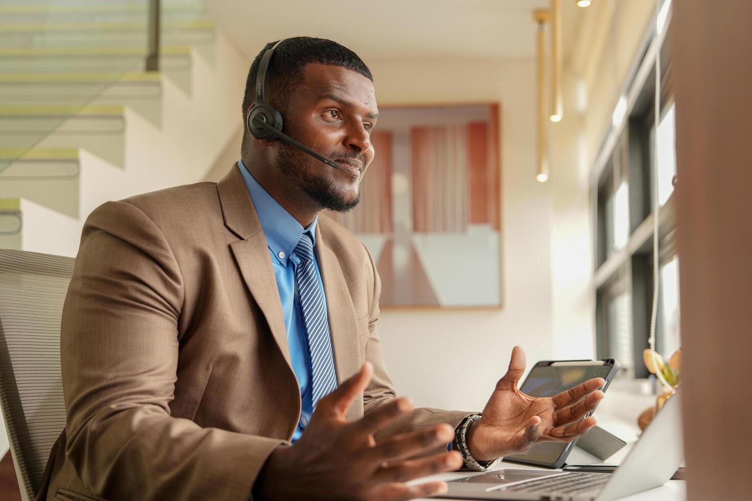 klant ondersteuning telefoontje centrum operator of receptioniste. klant onderhoud en Mens consultant pratend terwijl aan het doen een overleg online. Afrikaanse operator mannetje telemarketing middel Aan een laptop in kantoor foto