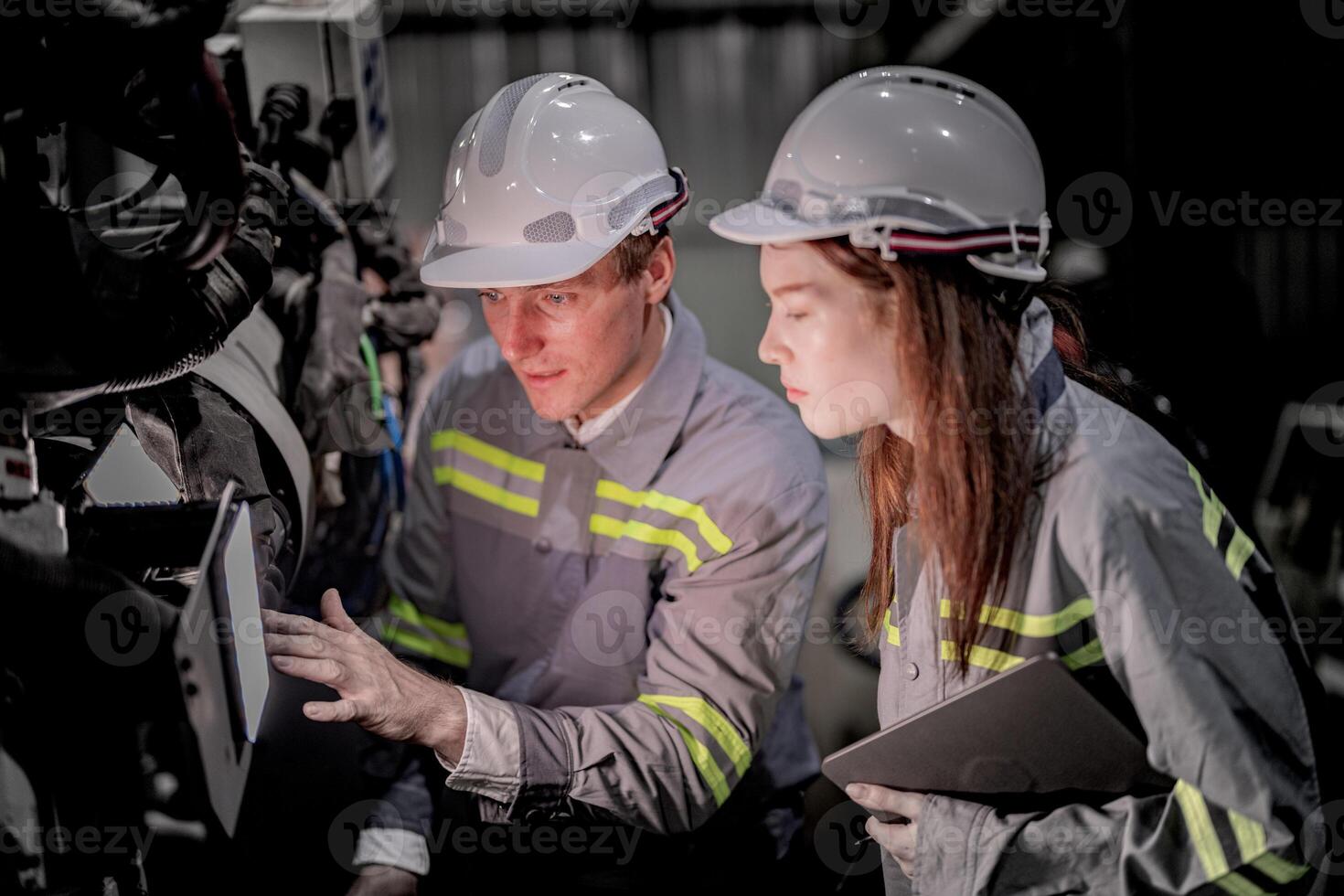 bedrijf ingenieurs ontmoeten en controleren controle zwaar machine robot arm. verschillend team van industrieel robotica ingenieurs verzameld in de omgeving van machine. professioneel machinerie operator gebruik industrieel digitaal tablet. foto