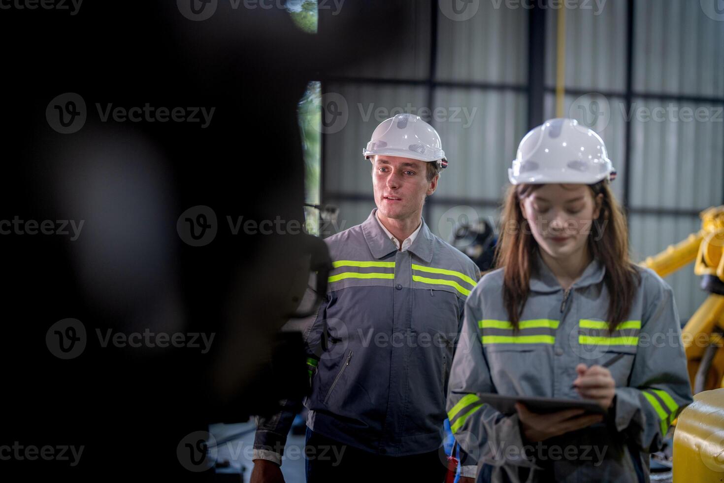 fabriek ingenieur vrouw inspecteren Aan machine met slim tablet. arbeider werken Bij machine robot arm. de lassen machine met een afgelegen systeem in een industrieel fabriek. kunstmatig intelligentie- concept. foto