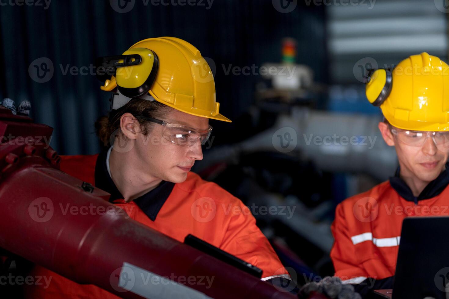 groep van mannetje ingenieur arbeiders onderhoud automatisch robot arm machine in een donker kamer fabriek. arbeider controle en repareren automatisch robot hand- machine. arbeider vervelend veiligheid bril en helm. foto