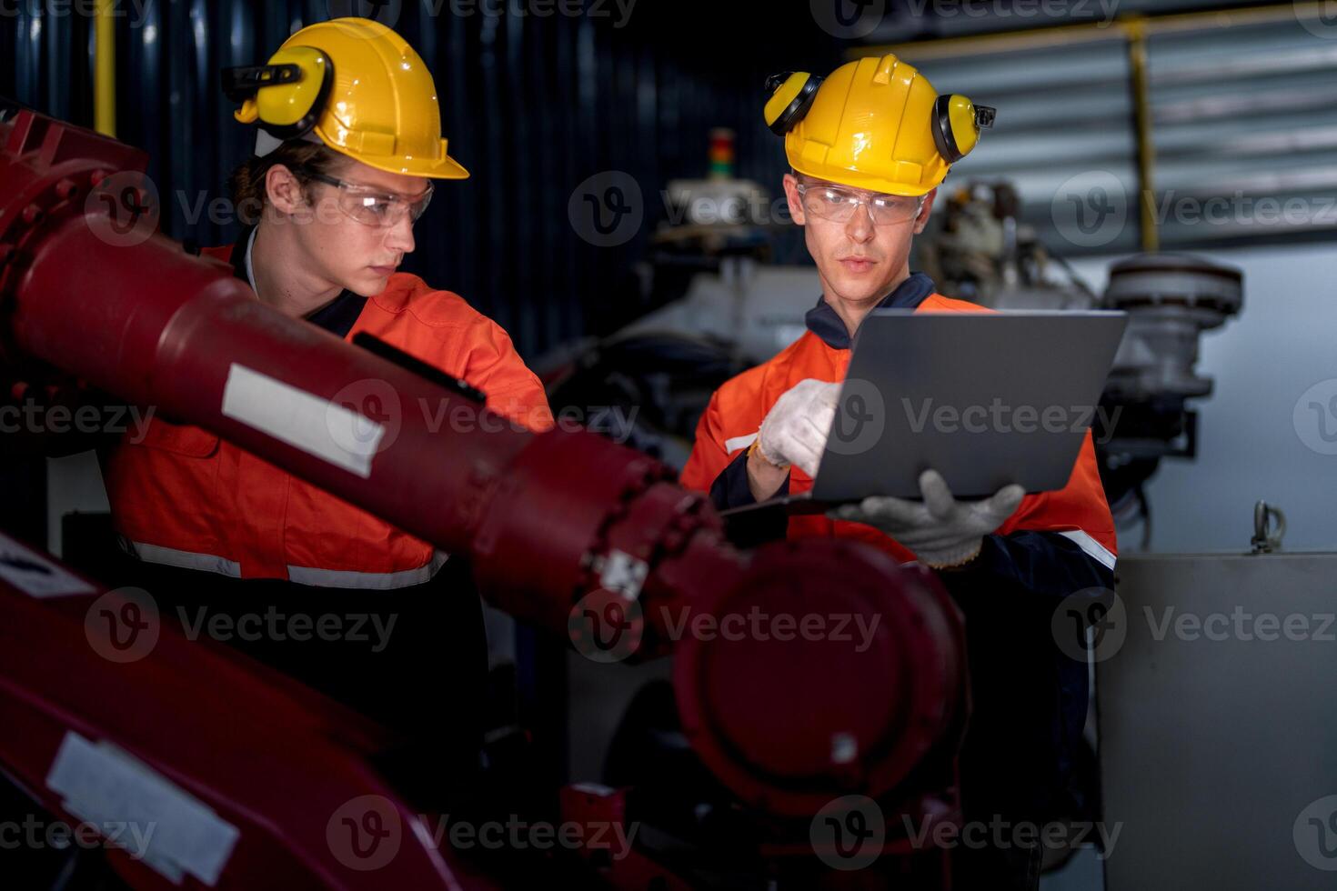 groep van mannetje ingenieur arbeiders onderhoud automatisch robot arm machine in een donker kamer fabriek. arbeider controle en repareren automatisch robot hand- machine. arbeider vervelend veiligheid bril en helm. foto