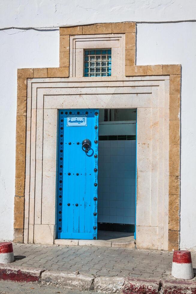 een blauw deur met zwart hengsten en steen ornament Bij deuropening in Tunesië foto