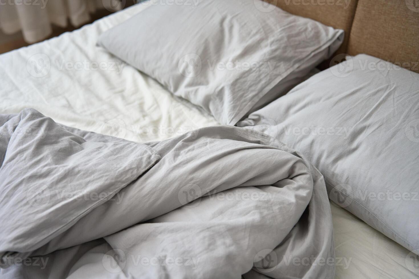 verfrommeld bed met kussens, deken en verfrommeld lakens in slaapkamer foto