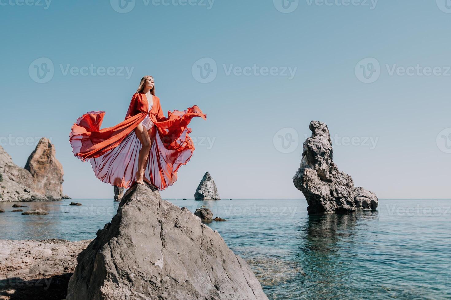 vrouw reizen zee. jong gelukkig vrouw in een lang rood jurk poseren Aan een strand in de buurt de zee Aan achtergrond van vulkanisch rotsen, Leuk vinden in IJsland, sharing reizen avontuur reis foto