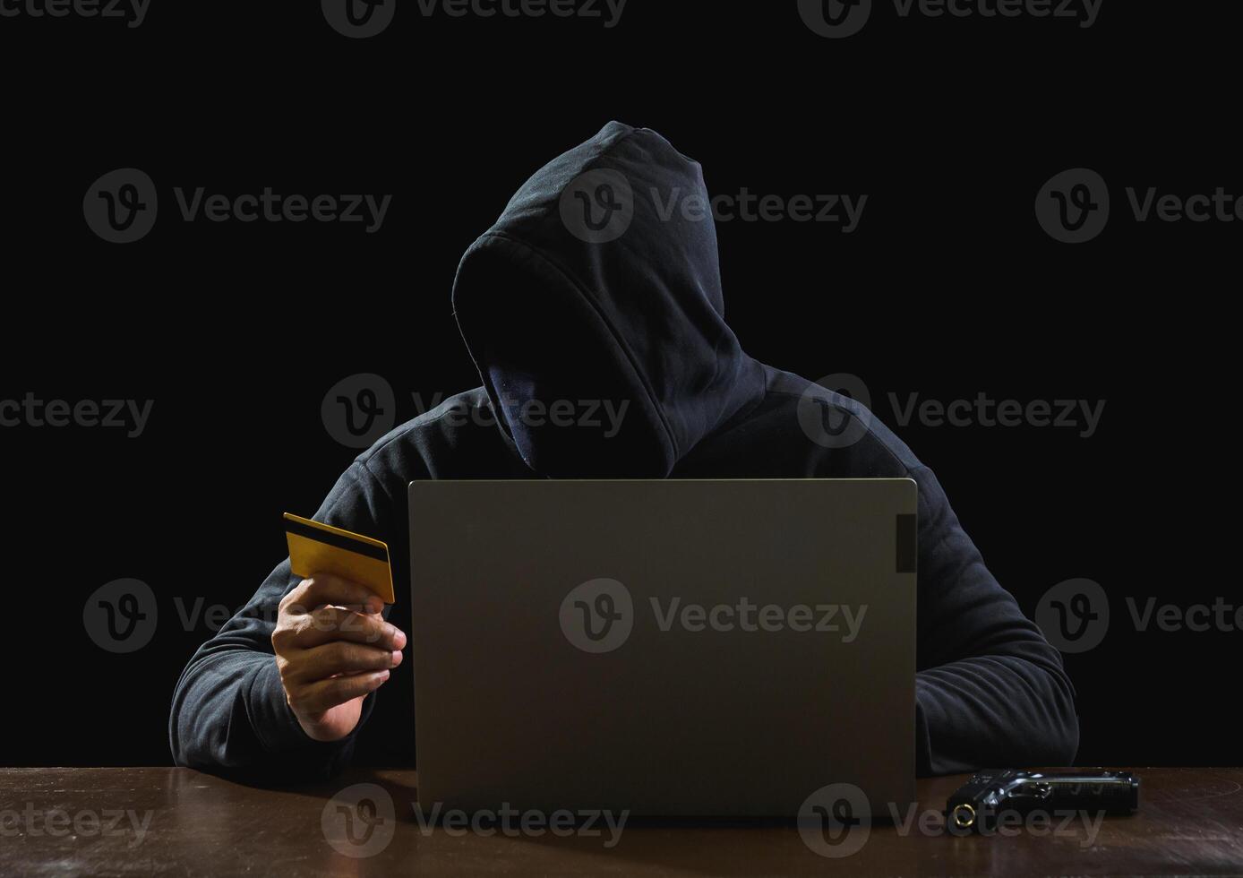 portret hacker spion Mens een persoon in zwart capuchon zittend Aan tafel op zoek computer laptop gebruikt Log in wachtwoord aanval veiligheid naar gegevens digitaal internet netwerk systeem nacht donker achtergrond kopiëren ruimte foto