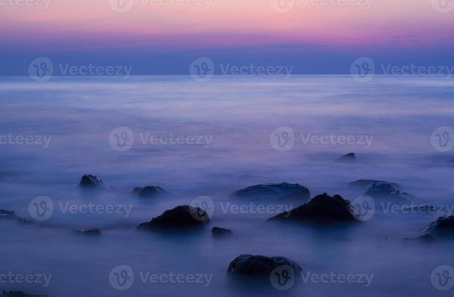 zachte golven op een rotsachtig strand in de avond foto