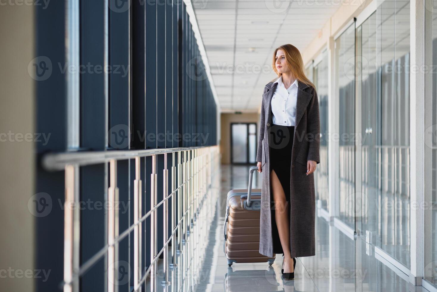 portret van geslaagd bedrijf vrouw op reis met geval Bij luchthaven. mooi elegant vrouw reizen met bagage. foto