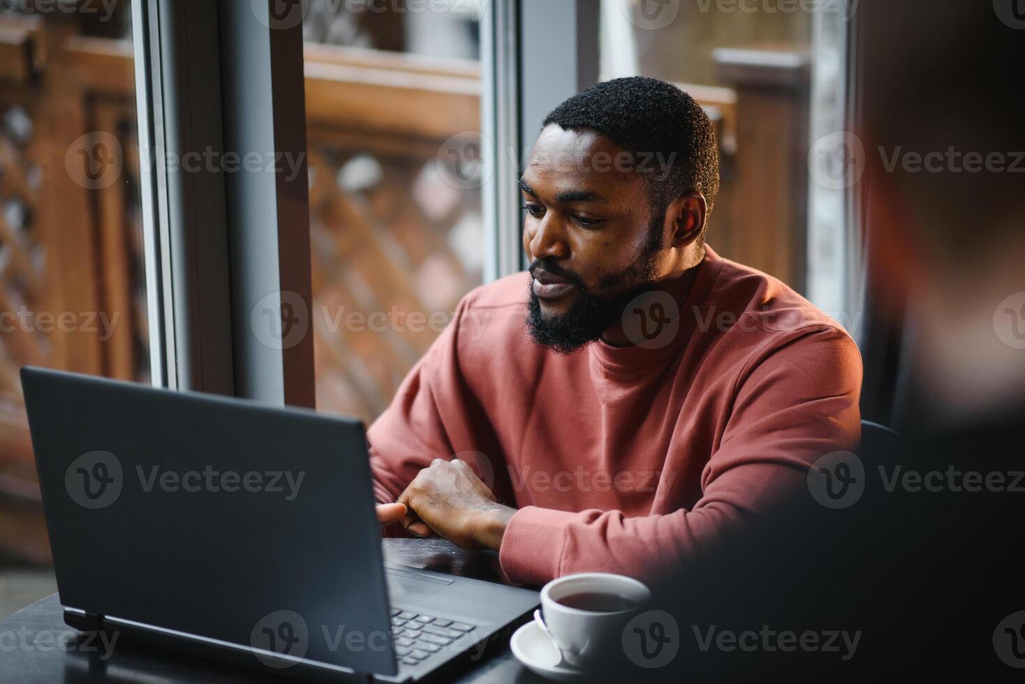 Afrikaanse Amerikaans Mens werken Aan laptop in een cafe. foto