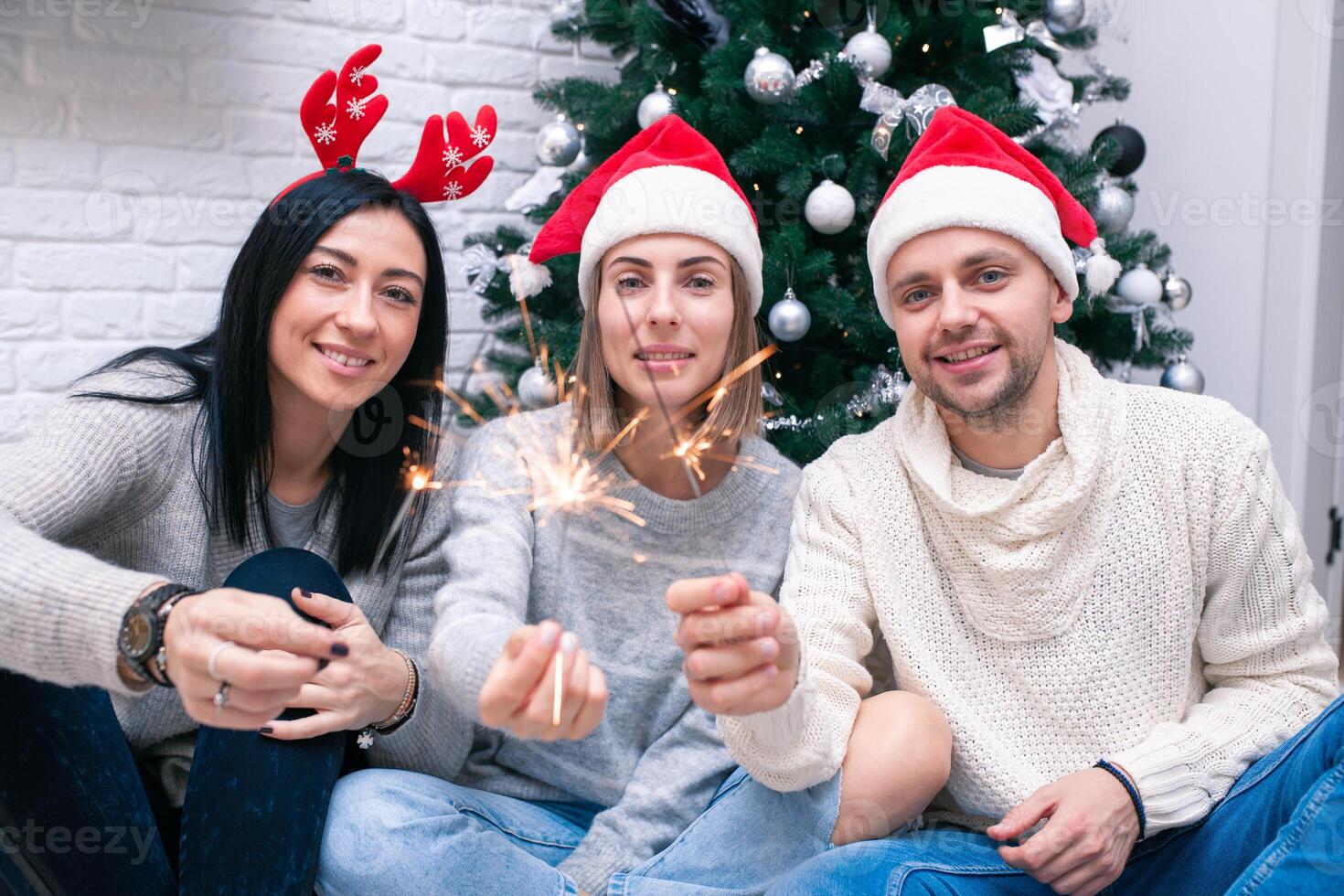 gelukkig vrienden vieren nieuw jaar in huis interieur in Kerstmis hoeden zittend in de buurt een foto