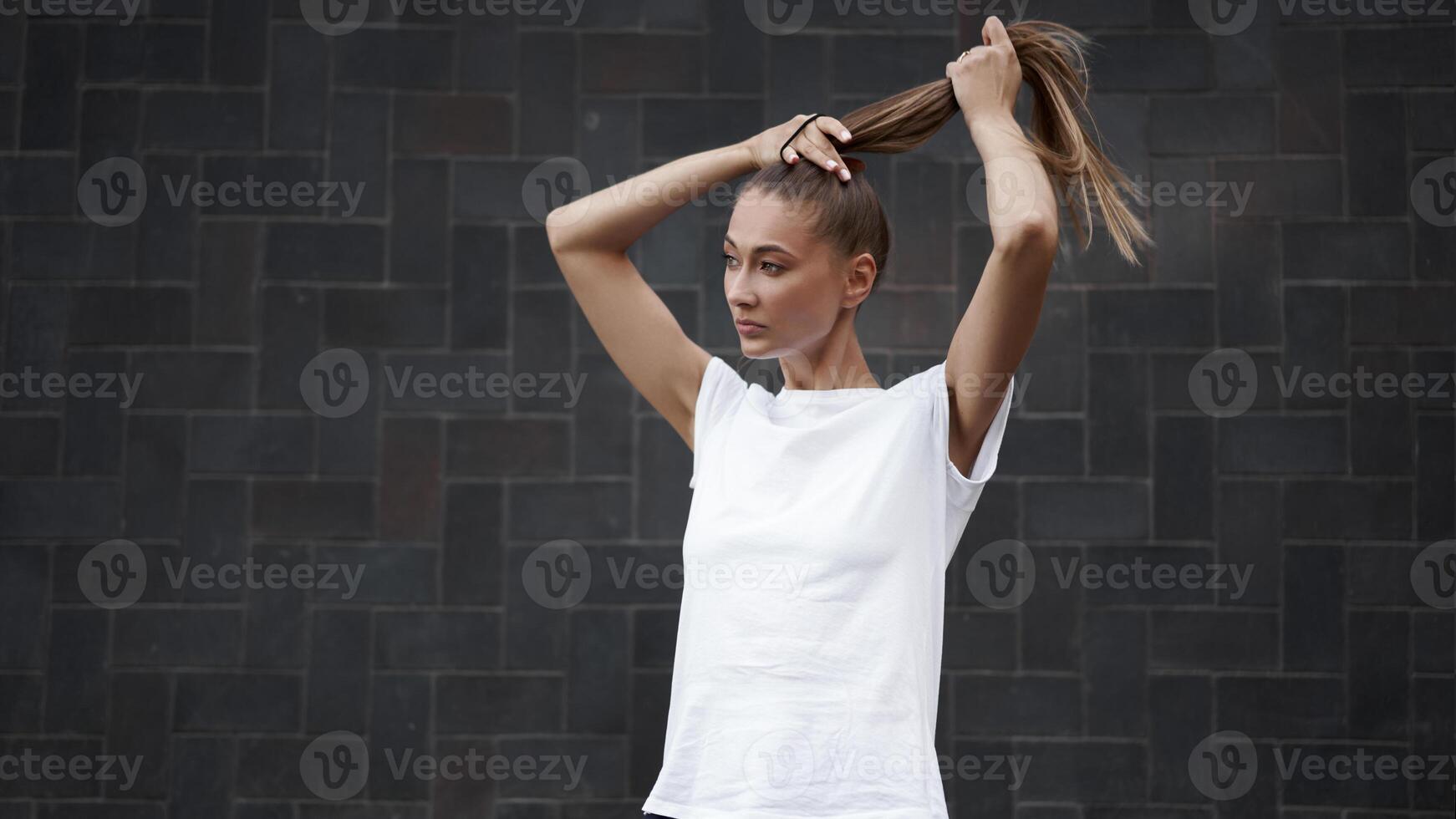 vrouw banden haar haar- in een paardenstaart voordat ochtend- training zwart muur achtergrond foto