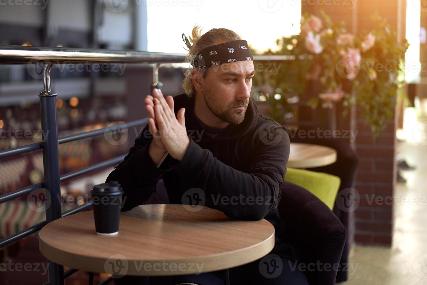 jong knap eenzaam Mens zit cafe tafel verdrietig aan het wachten voor vergadering drinken koffie van een papier beker. foto