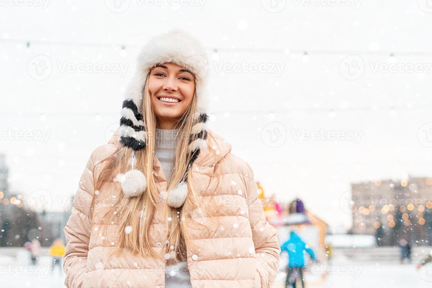 gelukkig winter tijd in groot stad charmant meisje staand straat gekleed grappig pluizig hoed. genieten van sneeuwval, uitdrukken positiviteit, glimlachen naar camera foto