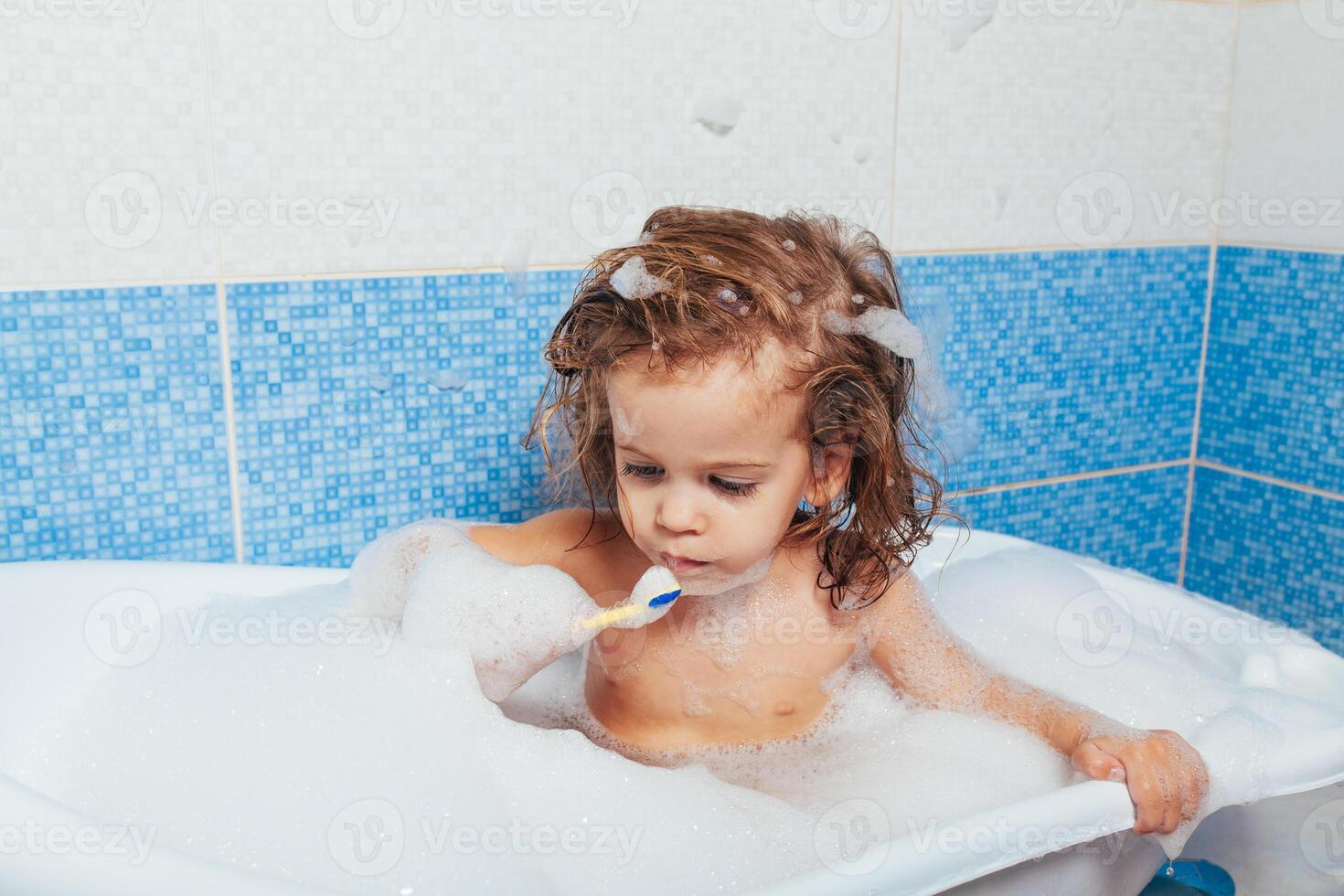 mooi jong meisje baadt in de badkamer en borstels haar tanden met een tandenborstel. dagelijks ochtend- routines. kinderen hygiëne is pret foto