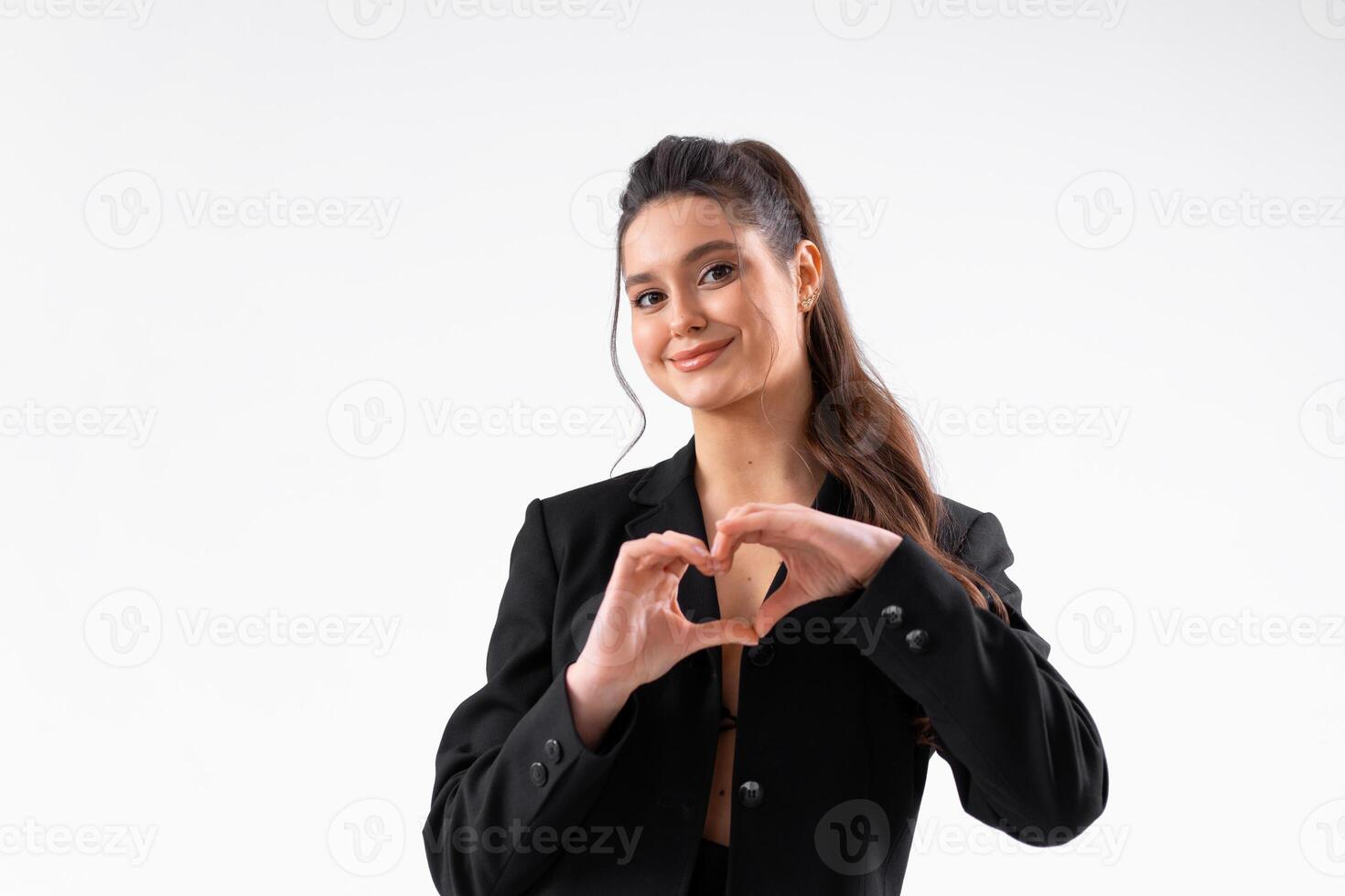 jong bedrijf vrouw tonen hart gebaar door hand- gekleed zwart jasje staand studio geïsoleerd Aan wit achtergrond foto