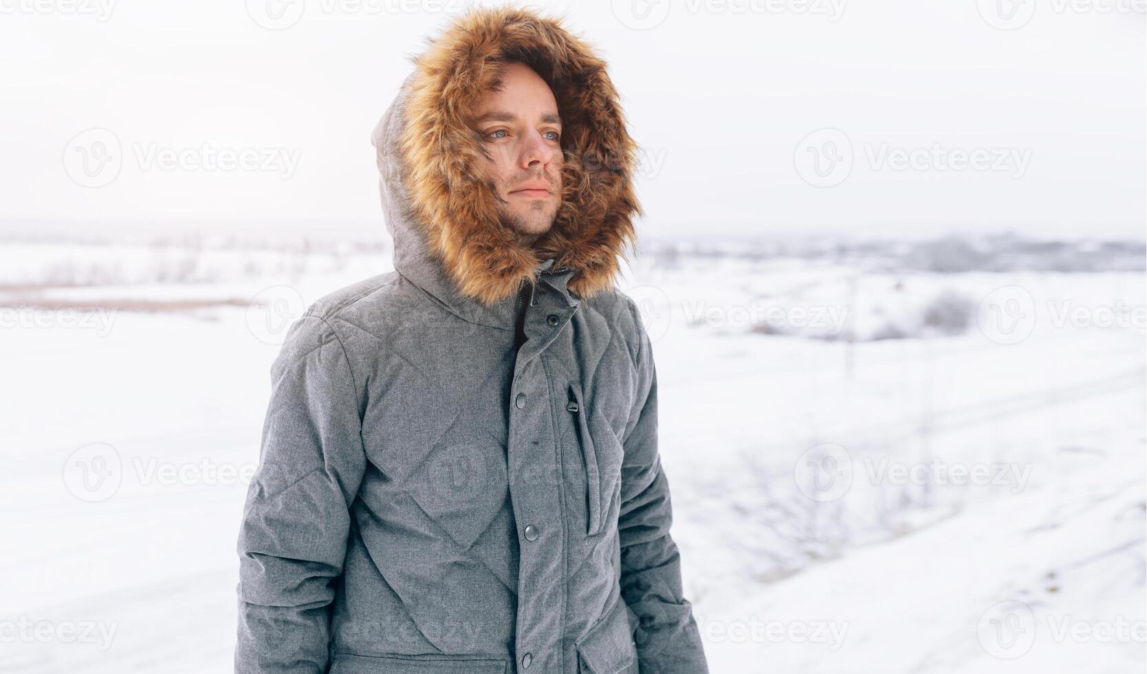 Mens vervelend grijs winter jasje met kap Aan in winter sneeuw foto