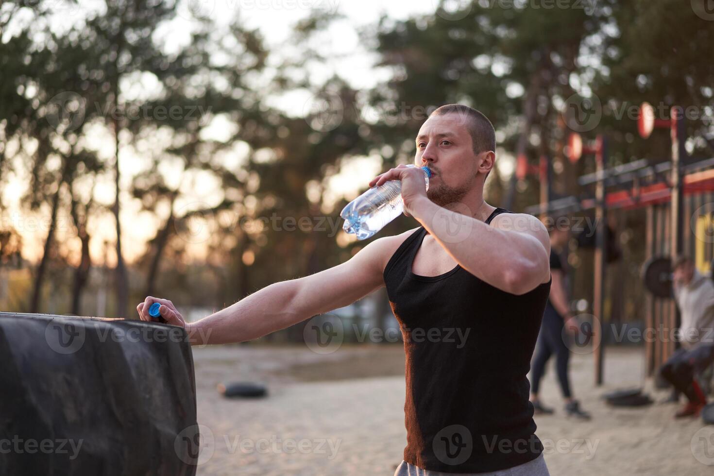 atleet Mens drinken water plastic fles training leunde Aan wiel band foto