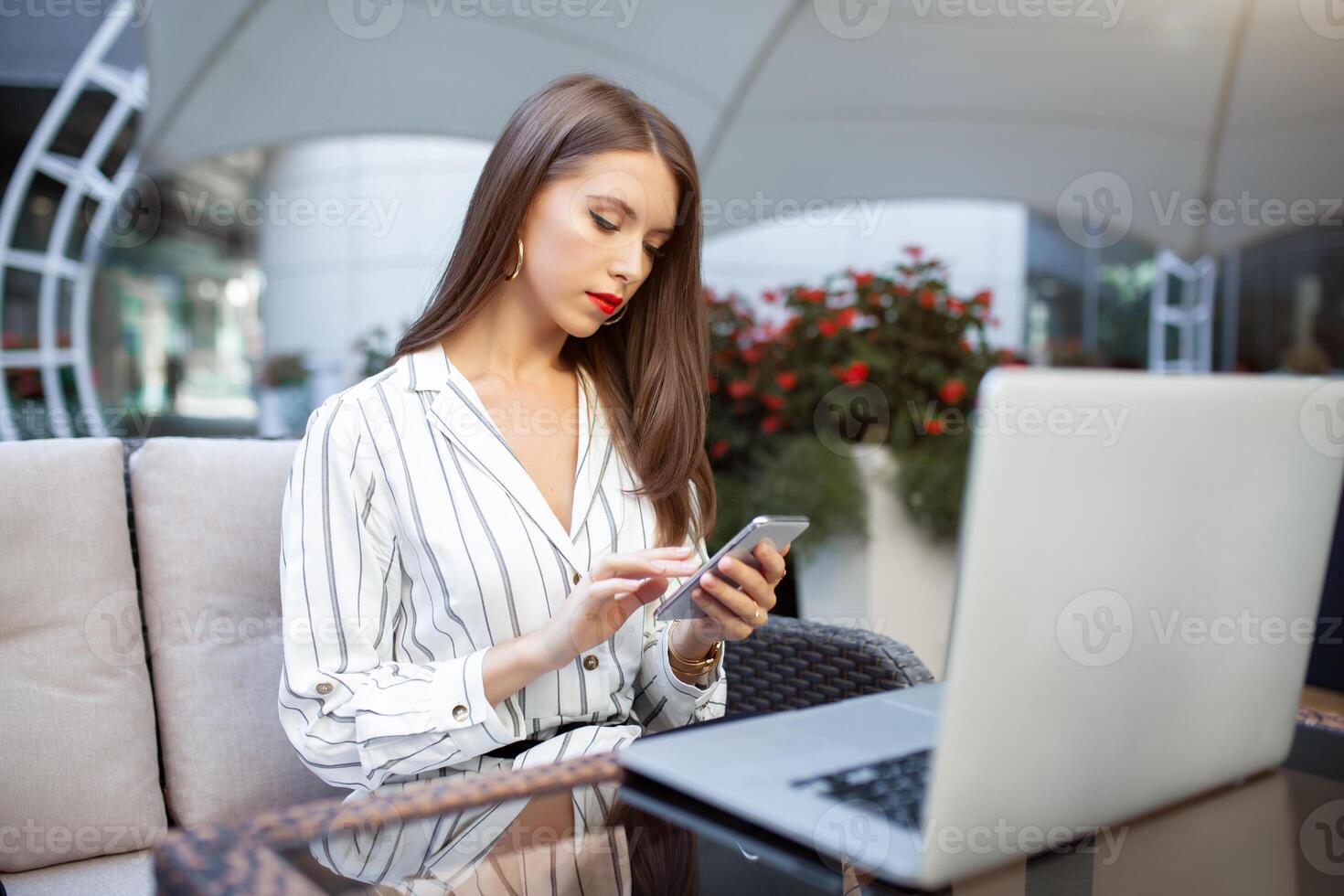 buitenshuis portret van Kaukasisch zakenvrouw gebruik makend van draadloze internet verbinding Aan laptop en gadgets, berichten via populair sociaal netwerken, gekleed terloops. mensen en technologie concept foto