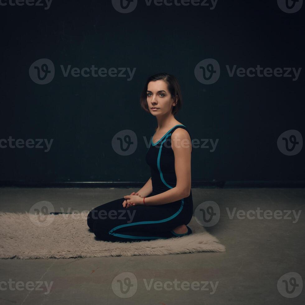 vrouw beoefenen yoga tegen een donker getextureerd muur foto