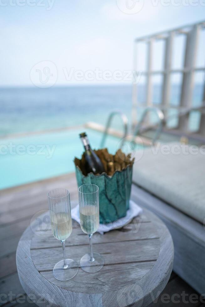 een Champagne fles Aan emmer gevulde met ijs Aan met tropisch oceaan achtergrond. foto