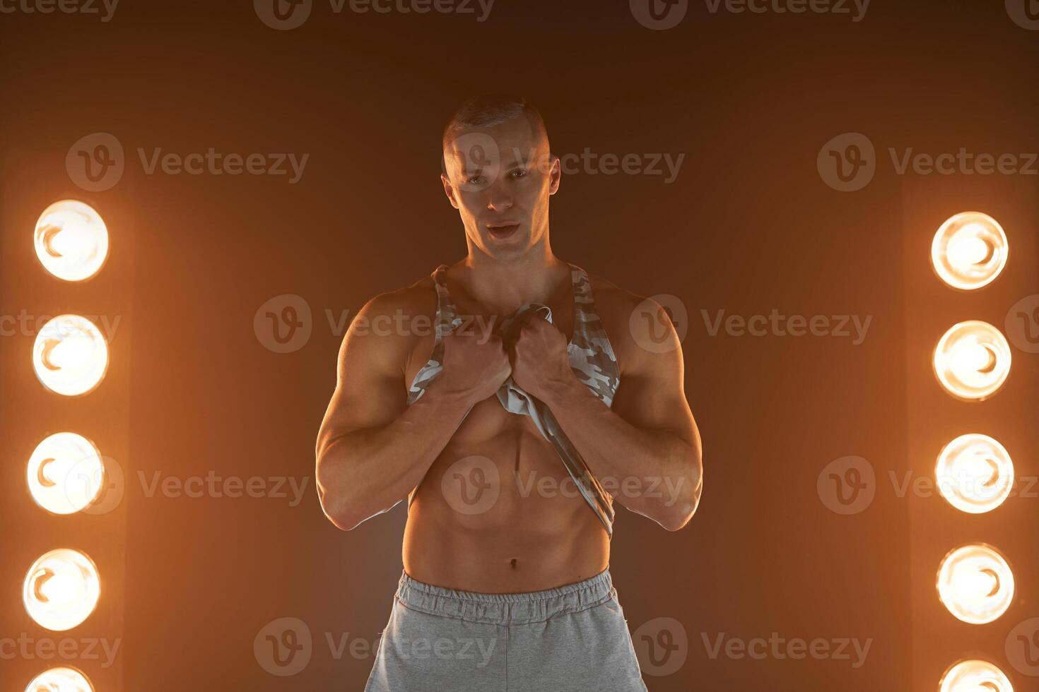 actief levensstijl concept. professioneel bodybuilder tonen buikspieren spier en op zoek Bij camera, lampen verlichting en rook Aan achtergrond foto