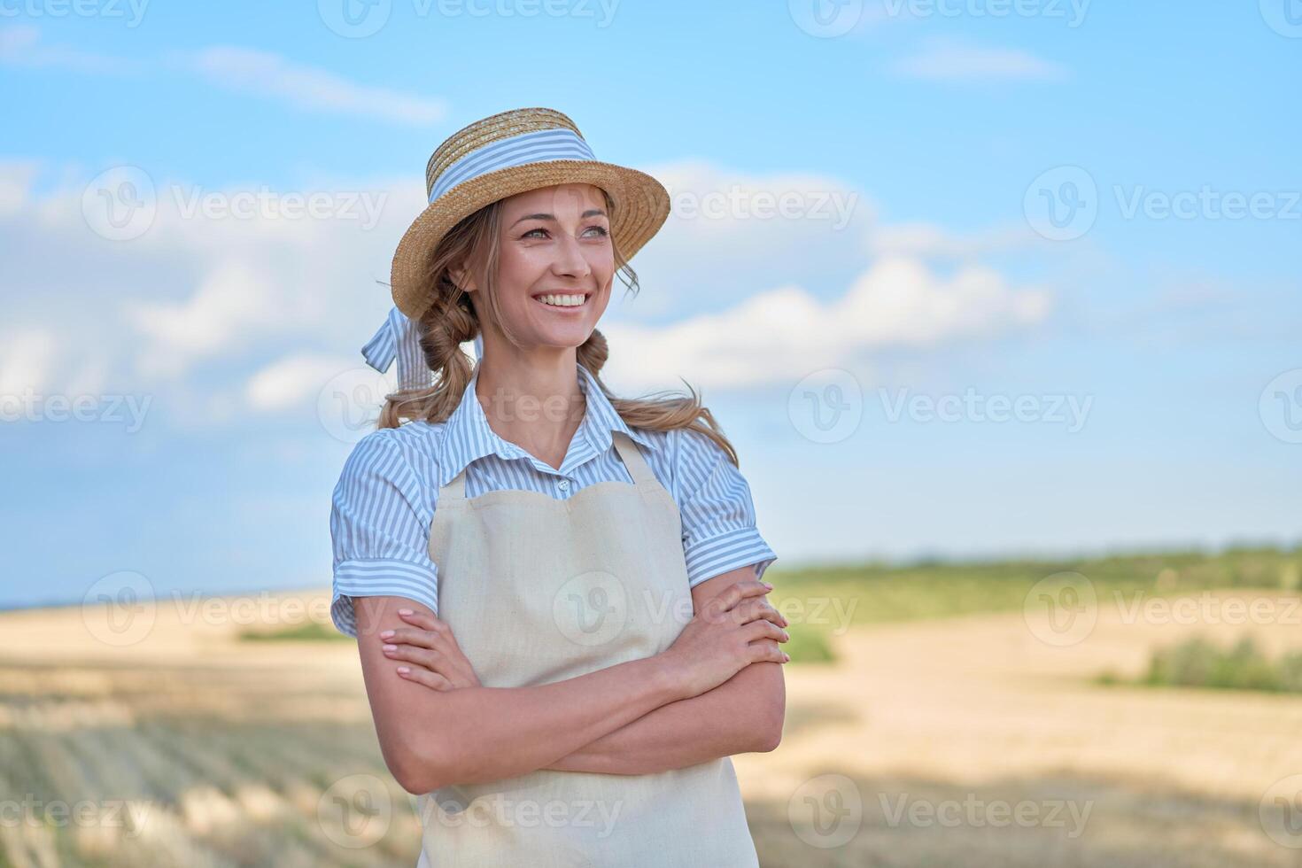 vrouw boer rietje hoed schort staand bouwland glimlachen vrouw agronoom specialist landbouw agribusiness gelukkig positief Kaukasisch arbeider agrarisch veld- foto